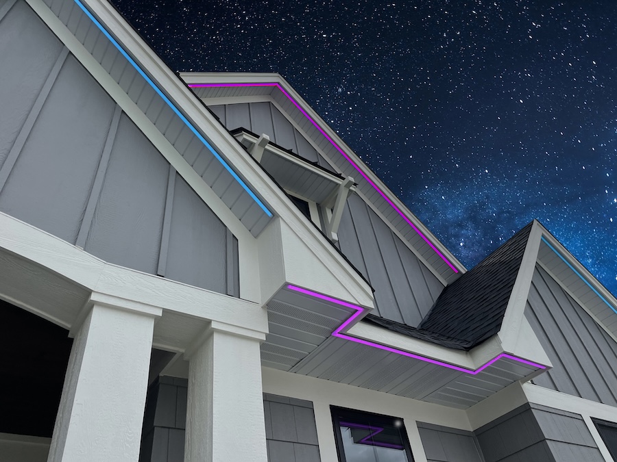 Home rooflines outlined in blue and pink permanent lighting against a starry night sky at Prior Lake.