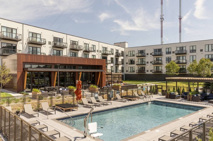 Apartment complex pool with lounge chair seating all around. Speakers and security cameras are camouflaged in the decor.