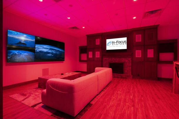 Media room lit in red with video wall and modern furniture