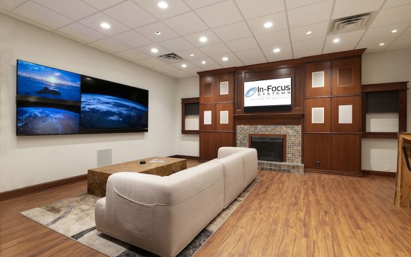 <span class="uk-h4">In-Focus Systems’ showroom showing a luxury couch and wall-mounted TV displays</span>