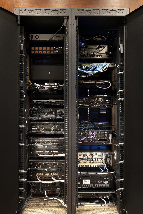 Open AV wiring rack with amplifiers, networking gear, and cabling